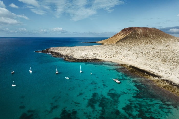 Playa de arena blanca en las islas canarias con veleros